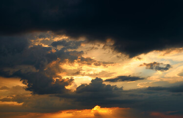 beautiful sunset sky, bright sun and dark silhouette of clouds as a background