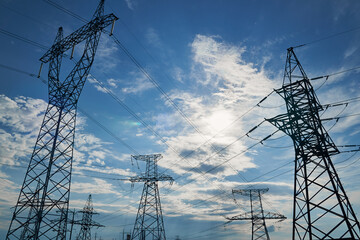 High-voltage electric lines, towers and industrial infrastructure against the blue sky