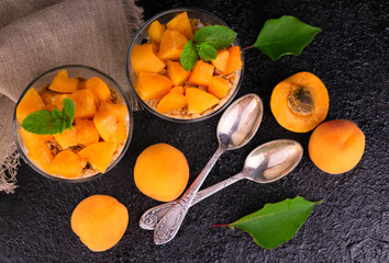 
Apricot yogurt with granola in a glass on a black background.
Flat lei.