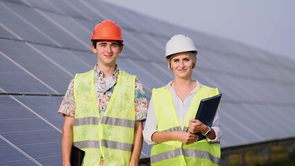 beautiful female engineer and young male trainee They are standing at a solar panel station. The female engineer teaches a young specialist who is undergoing practice
