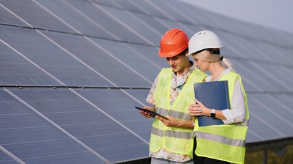 beautiful female engineer and young male trainee They are standing at a solar panel station. The...