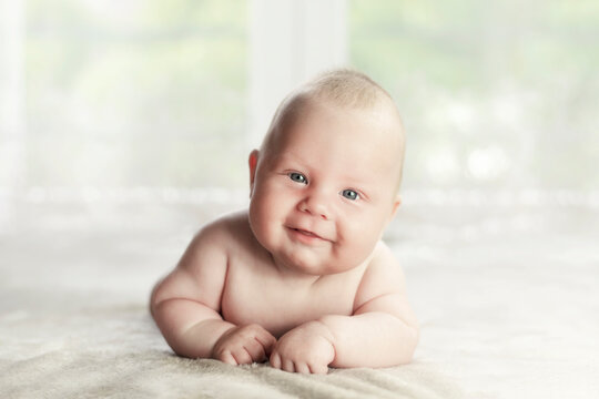 Three months old Caucasian boy lying on the belly with a raised head. Looking to the camera.