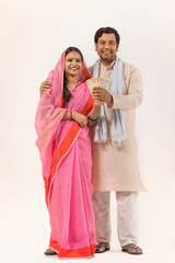 Fototapeta premium A MARRIED RURAL COUPLE POSING TOGETHER HOLDING MONEY