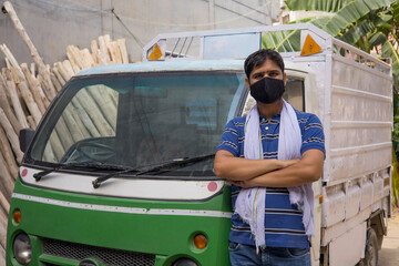 A LABOURER WEARING FACE MASK STANDING IN FRONT OF A VEHICLE
