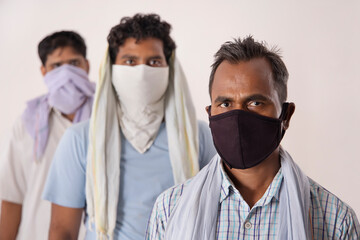 LABOURERS STANDING WITH FACE COVERED LOOKING AT CAMERA