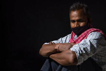 A LABOURER WEARING FACE MASK SITTING ALONE