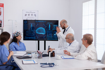 Neurologist showing digital radiography to medical coworkers analysing brain illness presentation using high tech in meeting room. Hospital team analyzing ill treatment examining healthcare expertise