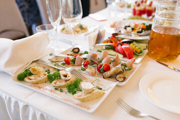 Snacks on white plates on a festive banquet table at a wedding