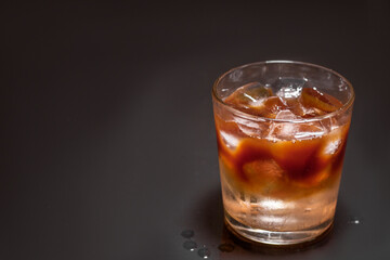 Iced coffee in a glass on black background. Cold refreshment summer drink