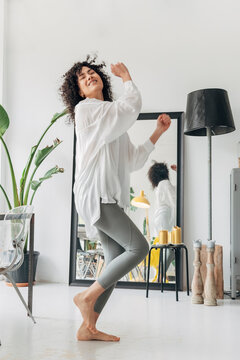 Young happy mixed race woman dancing at home with enjoyment.