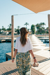 Woman walking on wooden pedestrian walkway at the beach. Travel concept