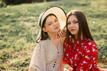 two beautiful young girlfriends in the summer park on the grass 