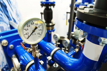 Pressure gauge on a piping system in an industrial boiler room. The mechanical pressure gauge...