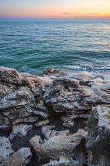 Colorful seaside sunset landscape with white stones in the foreground and red sky in the background. Summer leisure activity, tourism, travel, vacation, scenic destinations.