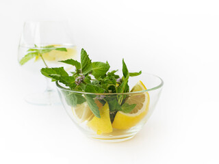 Wine glass with lemon-mint water and a glass bowl with mint and lemon wedges. Health theme. Antioxidants Nutraceuticals.