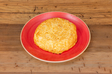 Small potato omelette served in a red plate on wooden table