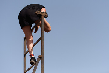 Participant in extreme obstacle race climbing over hurdle