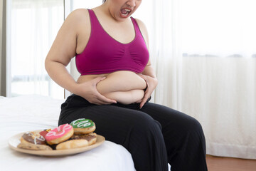 asian fat women , Fat girl , Chubby, overweight unhappy measuring her waist in the bedroom - Woman diet lifestyle overweight problem concept