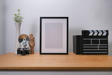 Front view with office desk concept, photo frame, clapper board and camera decorated on wooden table with white background.