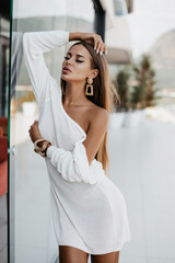 beautiful woman with dark hair in elegant dress and accessories posing outdoor