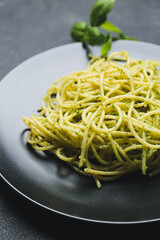 Plate with tasty pesto pasta on dark background, closeup