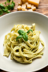 Plate with tasty pesto pasta on table, closeup