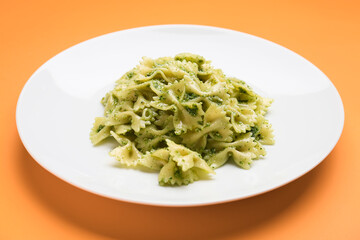 Plate with tasty pesto pasta on color background