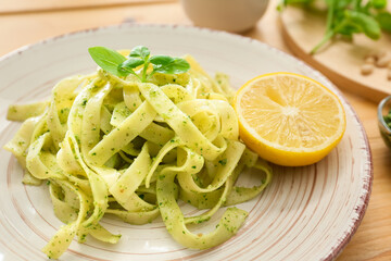 Plate with tasty pesto pasta on table, closeup
