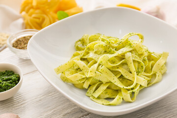 Plate with tasty pesto pasta on table