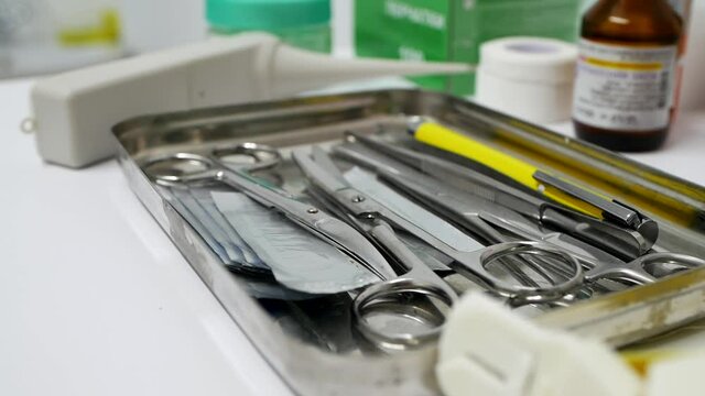 Close-up of shiny metallic medical instruments. Surgical instruments, scissors, forceps, scalpel, clamp are on the table at the surgeon's doctor.