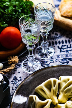 Overhead view of Georgian khinkali dumplings, bread and fresh salad with glasses of chacha