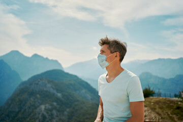 Naklejka premium Tourist man wearing face mask enjoying amazing mountains view, traveling vacation to Turkey during coronavirus epidemic
