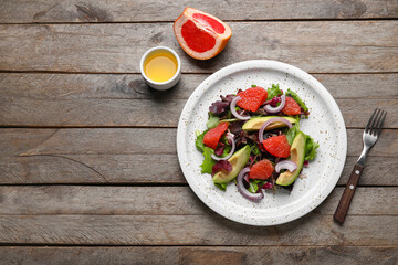 Plate with tasty grapefruit salad on wooden background