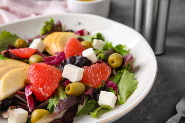 Plate with tasty grapefruit salad on grunge background, closeup