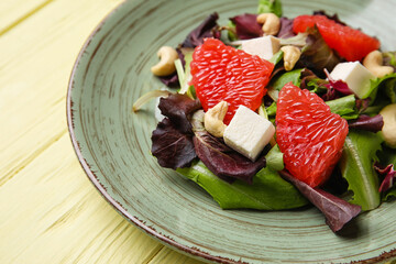Plate with tasty grapefruit salad on color wooden background, closeup