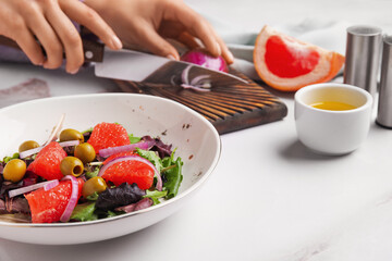 Woman making tasty grapefruit salad on table, closeup
