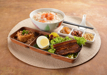 double boiled pumpkin rice congee porridge with braised pork belly , egg, fried bean curd tofu and peanut sour vegetable bento set on wood table asian halal menu