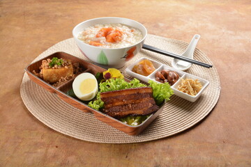 double boiled pumpkin rice congee porridge with braised pork belly , egg, fried bean curd tofu and peanut sour vegetable bento set on wood table asian halal menu