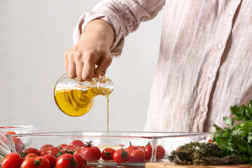 Woman preparing tomatoes and feta cheese for baking in kitchen