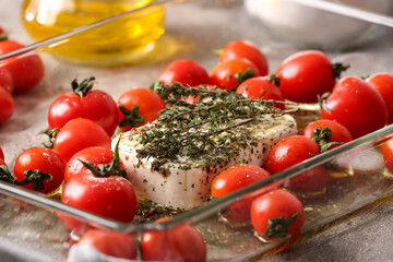 Baking dish with fresh tomatoes, feta cheese and spices on table