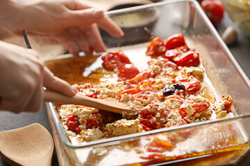 Woman preparing tomatoes and feta cheese in kitchen