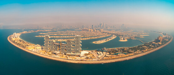 Panoramic aerial picture of the Palm Jumeirah artificial land in front of the Dubai coast on a sunny hazy day
