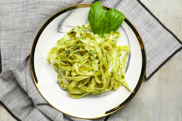 Plate with tasty pesto pasta on grunge background