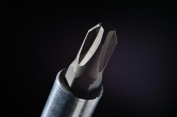 replaceable bit Phillips screwdriver on a black background close-up.