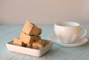 Sesame halva and cup of coffee on blue background. Traditional Middle Eastern sweets. Jewish, Turkish, Arabic national dessert. Turkish delight.A place to copy.