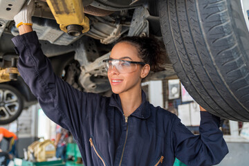 Female car mechanic enjoying work. Woman enjoying monitoring a car at the garage.