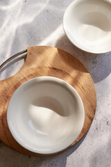 Empty white bowls on concrete, on a sunny table
