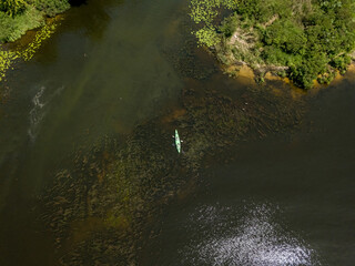 Kayak on a narrow river with green banks in summer. Aerial drone view.