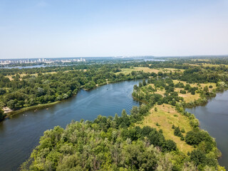 Fototapeta na wymiar River among green trees in summer. Aerial drone view.