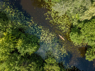 Kayak on a narrow river with green banks in summer. Aerial drone view.